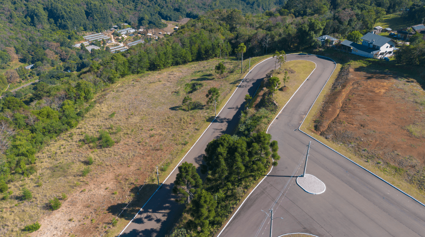 Life & Health — vista aérea de drone do acesso principal ao empreendimento, mostrando a via de entrada, terreno e vegetação nativa em Gramado, RS